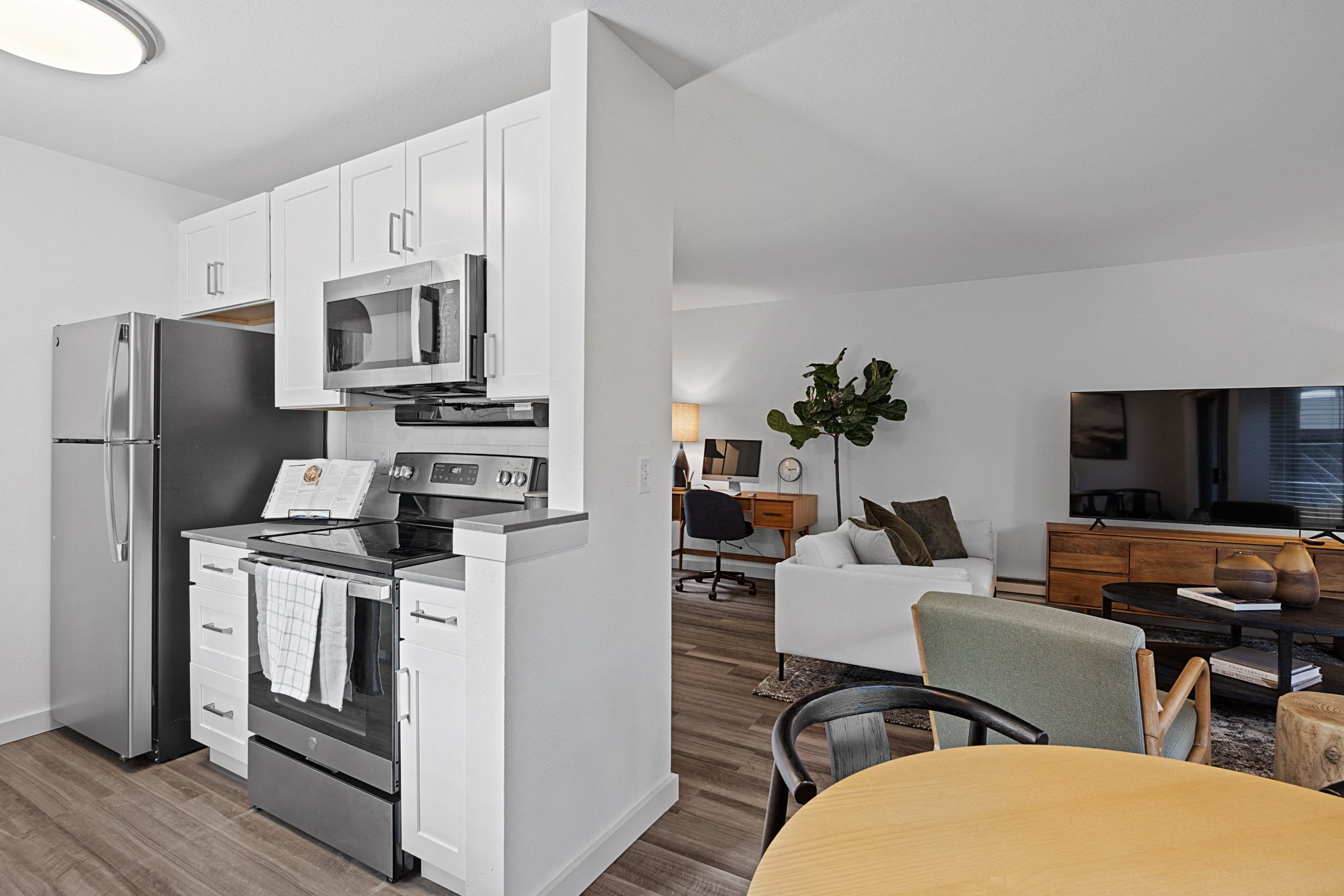 an open kitchen and living room with a dining room table and a refrigerator