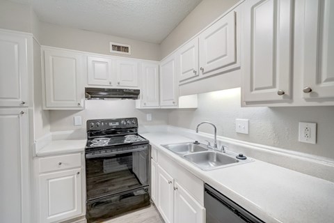 a kitchen with black appliances and white cabinets at Hills at Hoover 35216