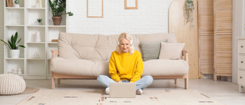 Woman renting alone researches neighborhoods on her laptop in a cozy apartment living room.