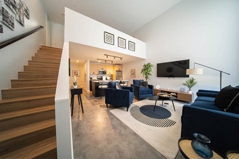 a living room with couches and chairs and a staircase