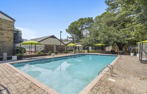 A large outdoor swimming pool surrounded by a brick patio and trees at The Onyx Hoover Apartments, Hoover, 35216