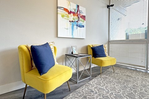 a living room with two yellow chairs and a table and a window