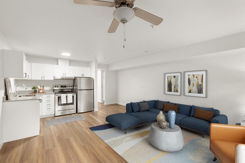 a living room with a blue couch and a kitchen in the background