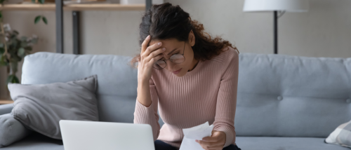 A frustrated person, holding some papers in hand, about to file a rental credit report dispute.