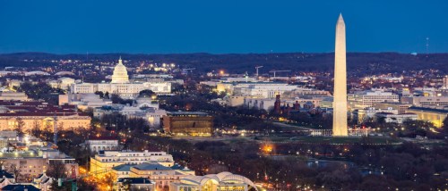 An aerial shot of Washington, D.C., after dark, with the Capitol building and Washington Monument lit up against the night sky.